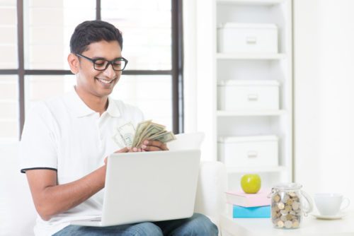 Online signature loans bad credit ok. A man sitting in front of a laptop holding money.